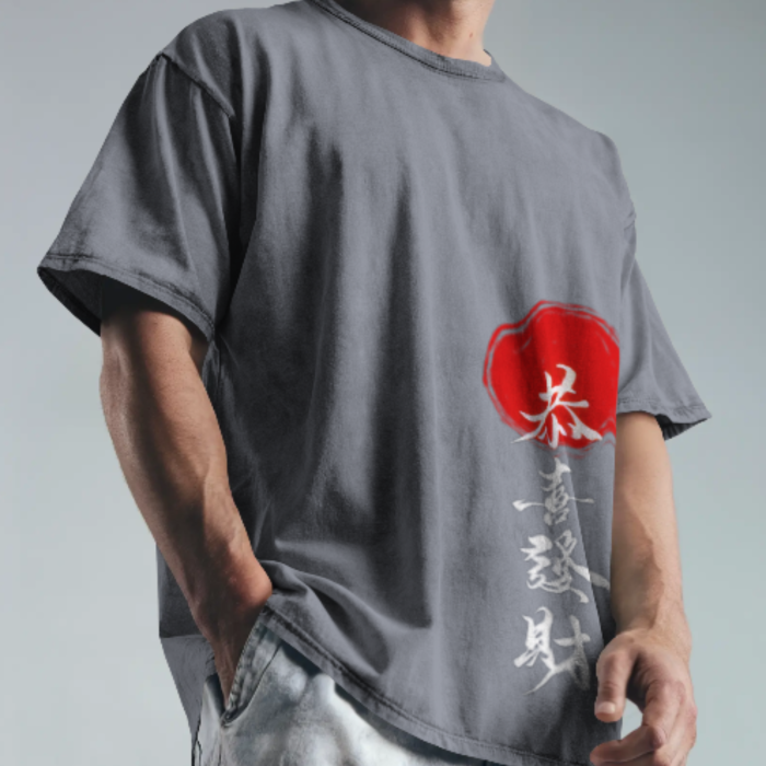 A man wearing a dark grey oversized t-shirt featuring Naruto bold white kanji text vertically aligned with a striking red stamp design. The background is neutral, keeping focus on the shirt’s design.
