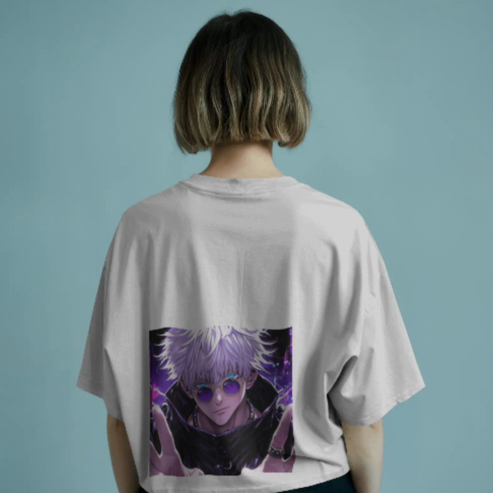 A woman wearing a white oversized T-shirt with a vibrant anime illustration of Satoru Gojo on the back. The art shows Gojo in his iconic shades and uniform, surrounded by a dark purple aura, hands outstretched mid-technique.